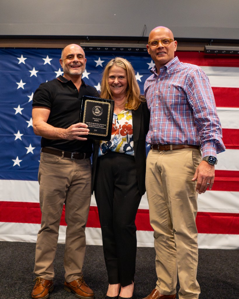 Bob's receives the Made in Medford honoree plaque on stage in front of an American flag.